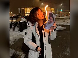 Mladá íránská �ena si zapaluje cigaretu o ho�ící fotografii íránského v�dce