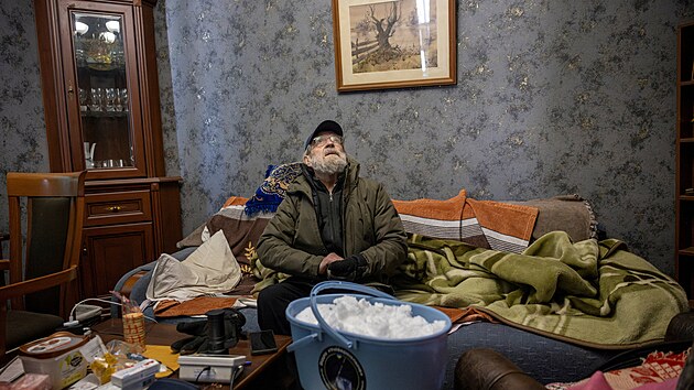 Serhij Pr�istovskij sed� ve sv�m ob�vac�m pokoji s kbel�kem sn�hu, kter� se chyst� p�es noc rozpustit, pot�, co jeho byt z�stal bez vody. (10. ledna 2026)