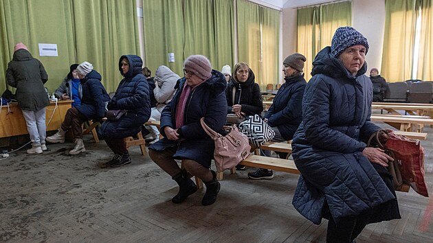 Lid� v Kyjev� se oh��vaj�, zat�mco �ekaj� na nabit� sv�ch mobil� ve vl�dn�m �tulku, kter� nab�z� z�kladn� slu�by a vyt�p�n� b�hem v�padk� proudu. (10. ledna 2026)