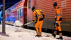 D�lníci odklízejí sníh z nástupi�t� na hlavním nádra�í po silném sn�ení v...