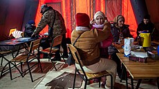 Lidé v Kyjev� se oh�ívají ve stanu, který poskytly záchranné slu�by, aby se...