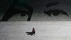 Mu� sedí na schodech zdobených nást�nnou malbou p�edstavující o�i zesnulého...