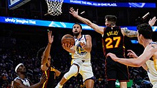 Stephen Curry zakon�uje pod ko�em p�es blok Víta Krej�ího.