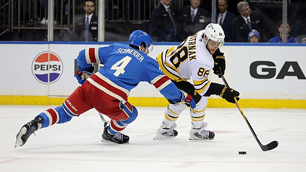 David Pastr��k z Boston Bruins si zpracov�v� kotou� p�ed Bradenem Schneiderem z New York Rangers.