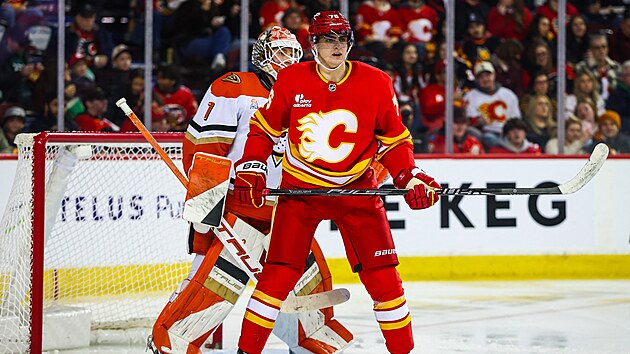 Luk� Dost�l z Anaheim Ducks vykukuje zpoza clon�c�ho Martina Posp�ila z Calgary Flames.