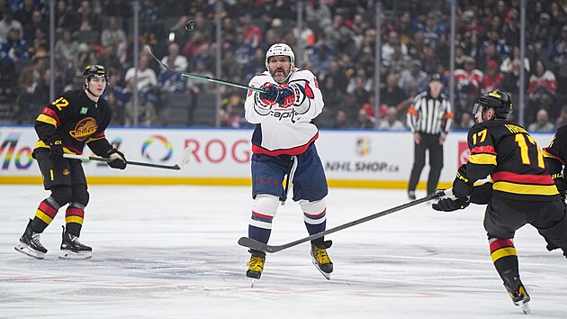 Alexander Ove�kin se natahuje po kotou�i, vpravo ho sleduje Filip Hronek.