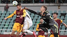 Branká� Rihards Matrevics z Dukly se sna�í vyrazit mí�, který p�ed ním odvrací...
