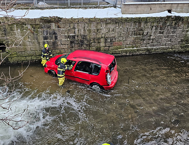 Auto po nehodě skončilo na boku v řece, zraněného řidiče zachránili hasiči
