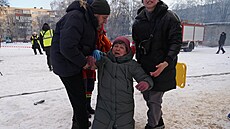 Sousedé pomáhají �en� poté, co dron zasáhl její byt v Charkov�. (3. února 2026)