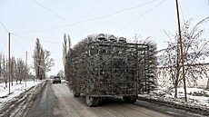 Vojenské auto oplocené elektrickou sítí na silnici s protidronovou sítí v...
