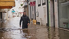 Obyvatel prochází zaplavenou ulicí poté, co �eka po silných de�tích v...