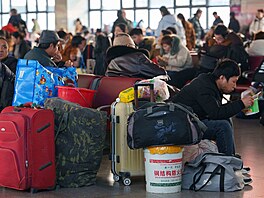 Na vlakovém nádra�í v Pekingu se cestující s velkými ta�kami a kufry tísnili v...