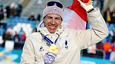 Zlatý medailista Quentin Fillon Maillet z Francie slaví s francouzskou vlajkou...