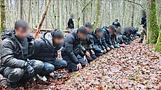 Se�azení migranti v lese poté, co byli zat�eni p�i výlezu z tunelu do Polska.