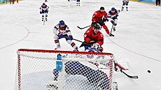 Macklin Celebrini z Kanady a Connor Hellebuyck ze Spojených stát� soupe�í o puk...