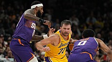 Rozehráva� Luka Don�i� (Los Angeles Lakers) se tla�í mezi dvojici bránících...