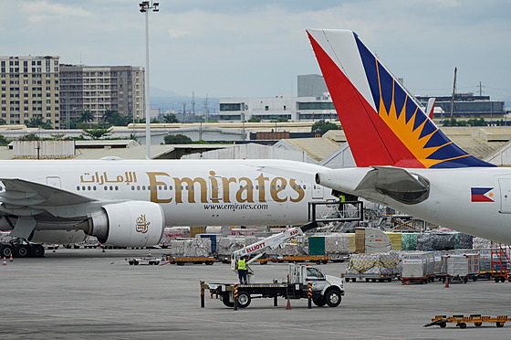 Mu� pracuje vedle zaparkovaného letadla spole�nosti Emirates na mezinárodním...