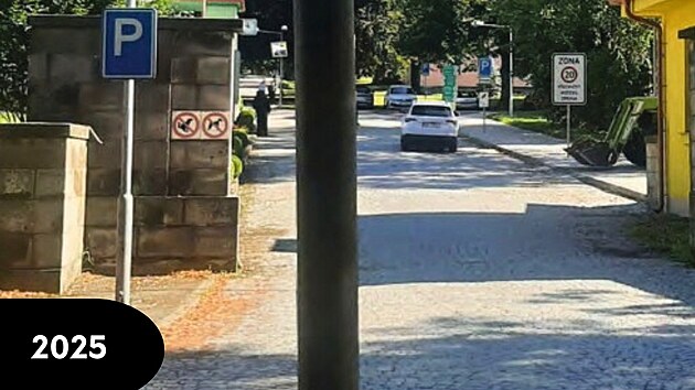 Stav 2025: Pohled do vjezdu do are�lu z ulice Rozko�sk�. Dominantou je nevzhledn� sloup ve�ejn�ho osv�tlen� v pop�ed�. Vlevo je vid�t betonov� ze� se zna�kou parkovi�t� a z�kazem vstupu se psy. Prostor za vjezdem slou�� pro parkov�n� aut.