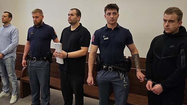 Trojice ob�alovan�ch z v�roby nebezpe�n� nov� drogy v soudn� s�ni za asistence justi�n� str�e. (13. b�ezna 2026)