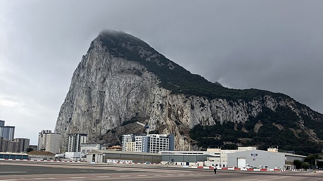 Gibraltarsk� sk�la s vrcholkem zahalen�m v mlze, a p�ed n� leti�tn� ranvej, po kter� lze p�ej�t.