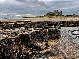 Temná silueta hradu Bamburgh, ost�e se rýsující se proti horizontu, p�sobí a�...