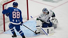 Branká� Kevin Lankinen z Vancouver Canucks se otá�í za Martinem Ne�asem z...