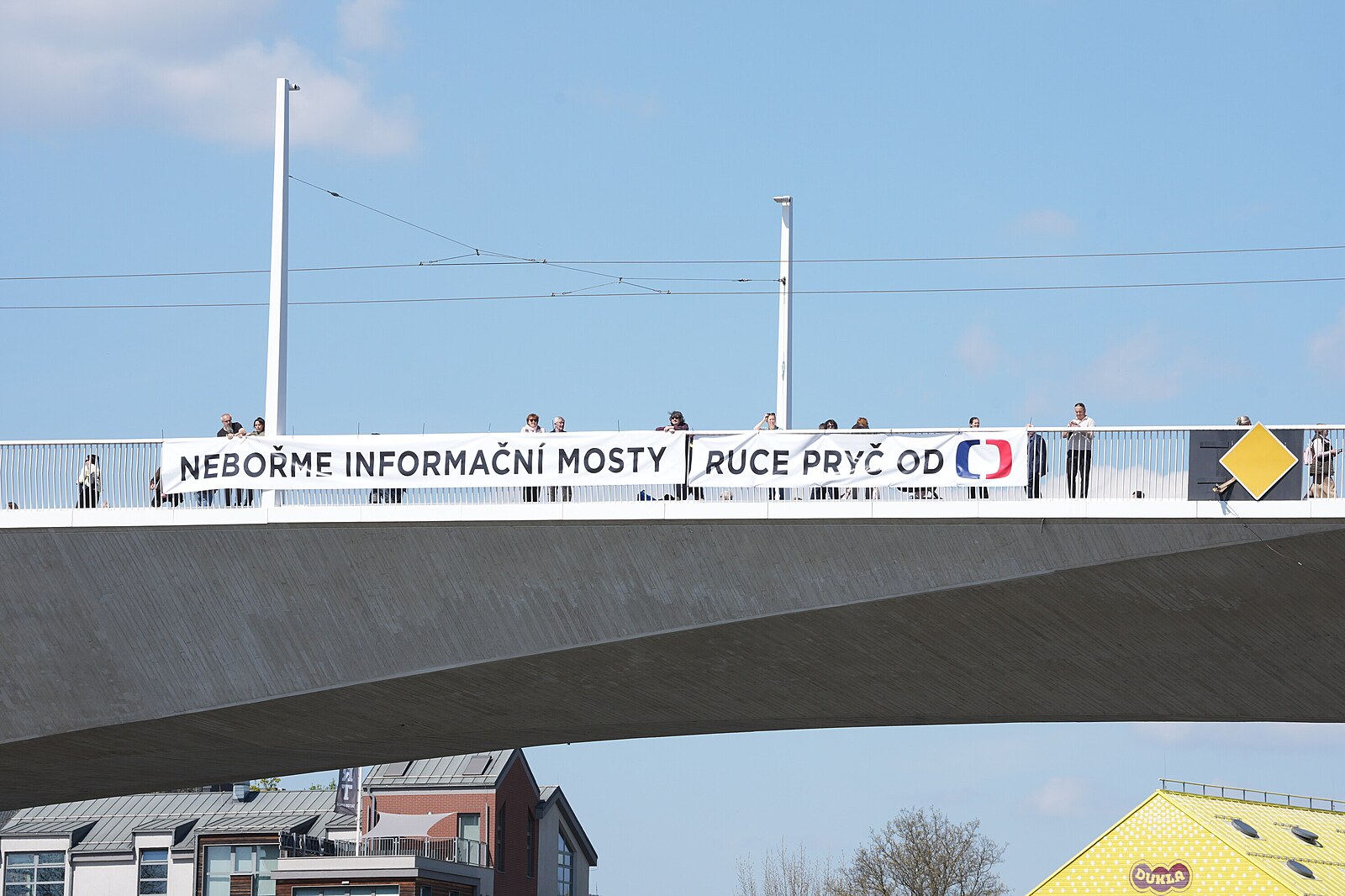 Ruce pryč od ČT. Spolek Kaputin rozvinul na nově otevřeném mostě transparent
