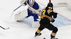 Bostonský Fraser Minten v �anci p�ed branká�em Alexem Lyonem z Buffala