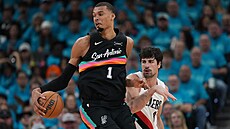 Victor Wembanyama vymý�lí akci, sna�í se ho bránit Deni Avdija.