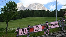 Plot vítající peloton Gira s dolomitskými vrcholky v pozadí.