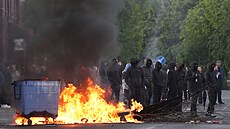 Maskovaní demonstranti stojí u ho�ících kontejner� na ulici Ligoniel Road v...