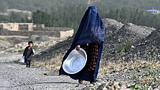 Afghánská �ena v burce nese nádobu ulicí v okrese Argo v provincii Badach�án....