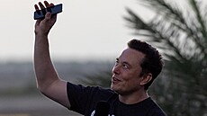 Elon Musk zvedá telefon k obloze na tiskové konferenci SpaceX 25. srpna 2022