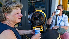 Zákaznice londýnské kavárny vybavené p�enosným akumulátorovým ventilátorem....