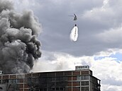 Vrtulník UH-60 Black Hawk hasí po�ár jedné z budov v bývalém ba�ovském továrním...