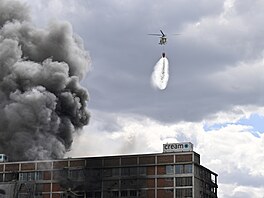 Vrtulník UH-60 Black Hawk hasí po�ár jedné z budov v bývalém ba�ovském továrním...