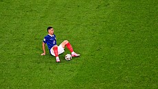 Francouzský fotbalista William Saliba sedí na trávníku po zran�ní v utkání...