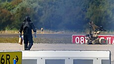Policista v ochranném obleku prochází kolem pyrotechnického robota na leti�ti...