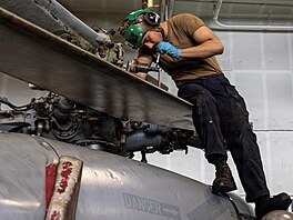 Americký námo�ník provádí údr�bu vrtulníku MH-60S Sea Hawk v hangáru letadlové...