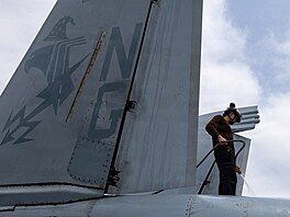 Americký námo�ník myje letoun EA-18G Growler na palub� letadlové lodi t�ídy USS...