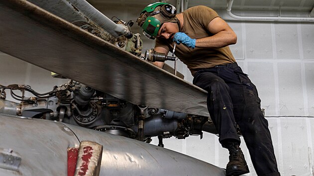 Americk� n�mo�n�k prov�d� �dr�bu vrtuln�ku MH-60S Sea Hawk v hang�ru letadlov� lodi USS Abraham Lincoln. (9. srpna 2026)