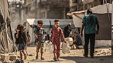 Palestinské d�ti nesou nádoby s vodou mezi stany pro vysídlené obyvatele ve...
