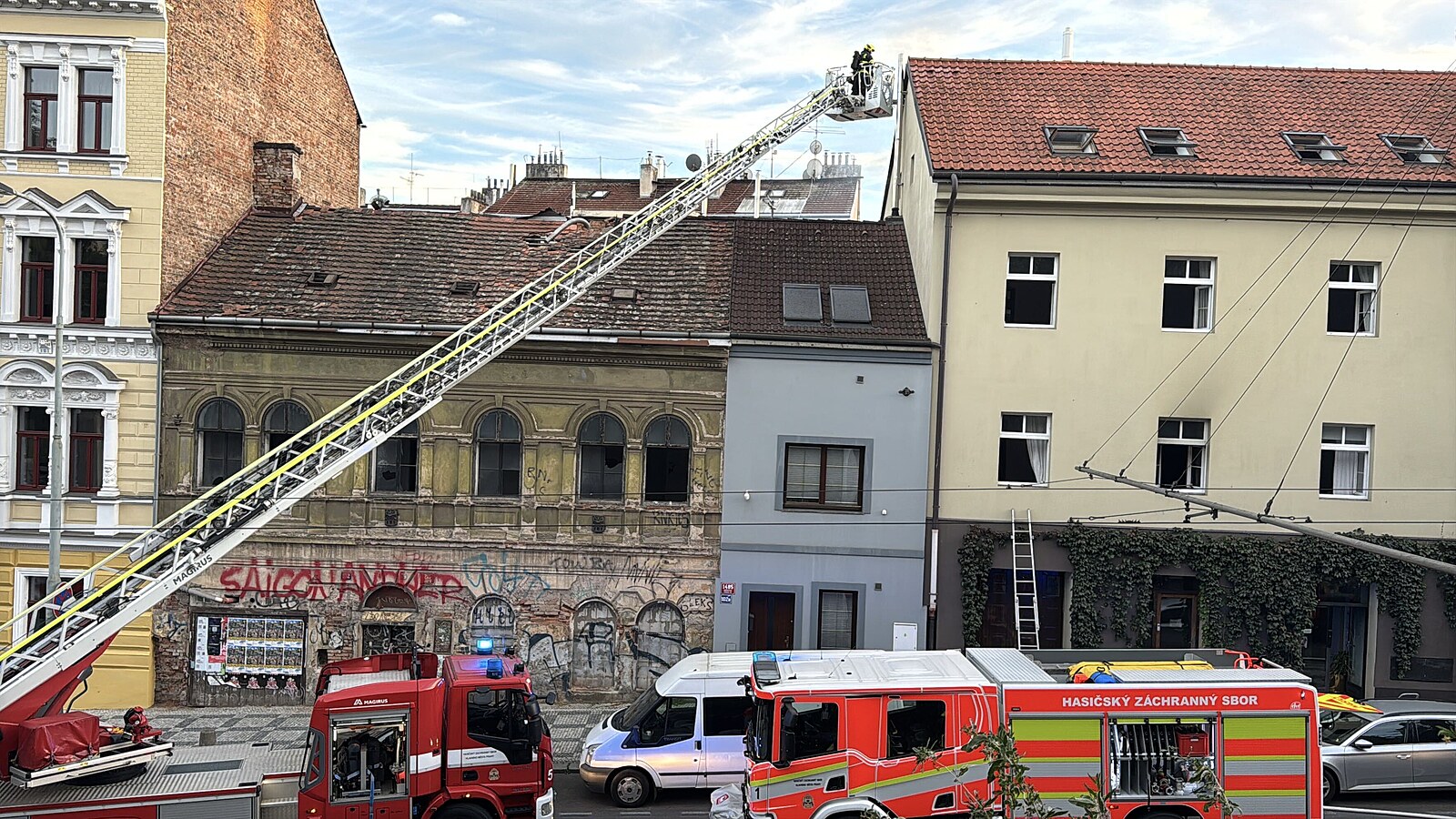Požár v domě na pražských Vinohradech. Hasiči evakuují lidi, ulice je zcela uzavřena