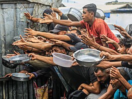 Palestinci se shroma��ují v distribu�ním centru, aby si vyzvedli teplá jídla...