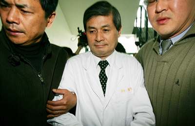 Slavný jihokorejský vědec U Sok-hwang (uprostřed) v doprovodu svých strážců opoučtí tiskovou konferenci