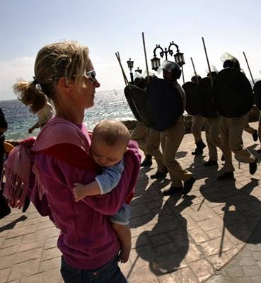 Turistka s díttem míjí policisty v egyptském letovisku Dahab, kde dolo k teroristickému útoku.