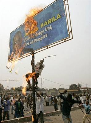 Píznivci Etienna Tshisekediho zapalují billboard Josepha Kabily.