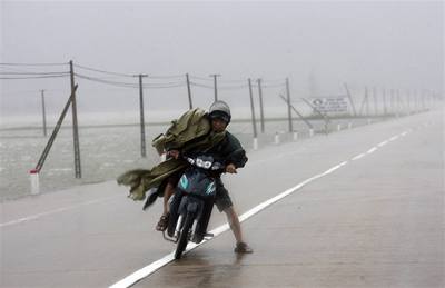 Vietnamský motocyklista svádí souboj s vtrem.