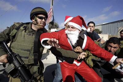 Jeíovo rodit: nepokoje i o Vánocích. Izraelský policista zasahuje proti palestinským demonstrantm, z nich jeden je obleen jako Santa Claus.