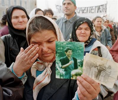 Muslimsk ena s fotografiemi svch pbuznch zabitch pi masakru v Srebrenici.